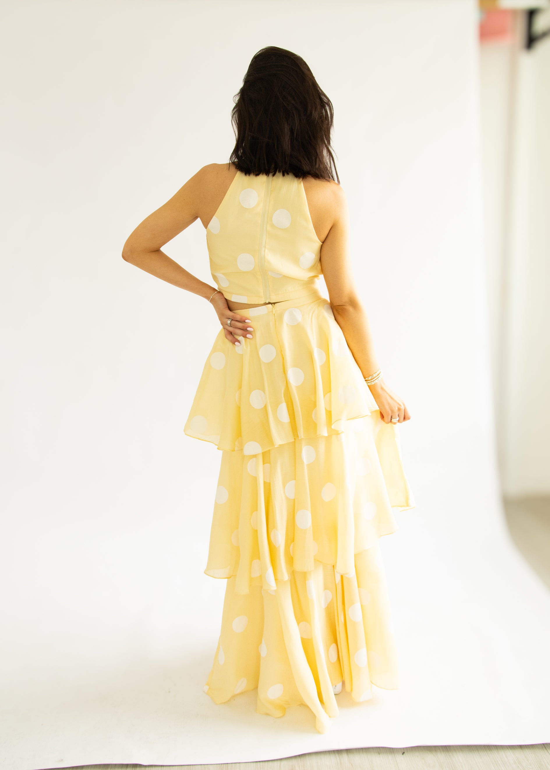 Woman wearing a yellow polka dot dress against a white background