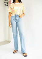 Person wearing a striped shirt and light blue jeans on a white background