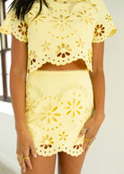 Yellow floral cut-out outfit on a person against a neutral background