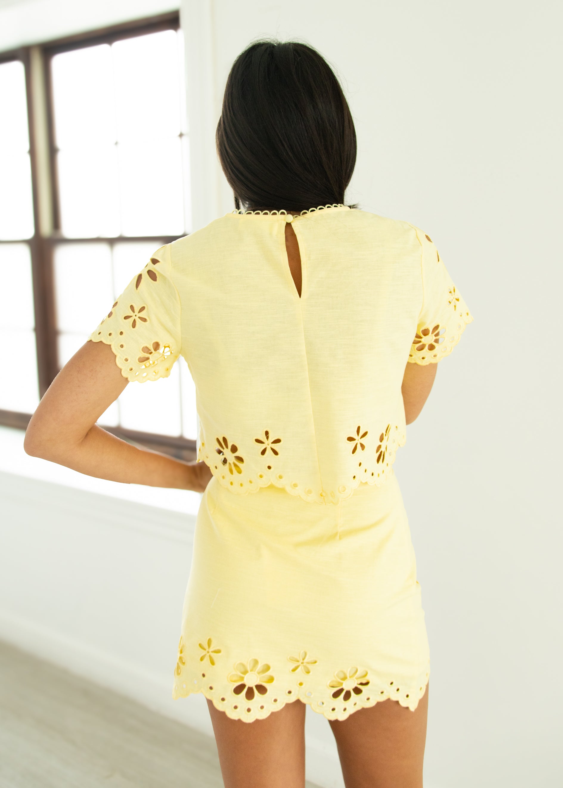 Woman wearing a yellow set with floral cut-out details.