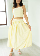 Woman wearing a light yellow two-piece outfit in a minimal indoor setting