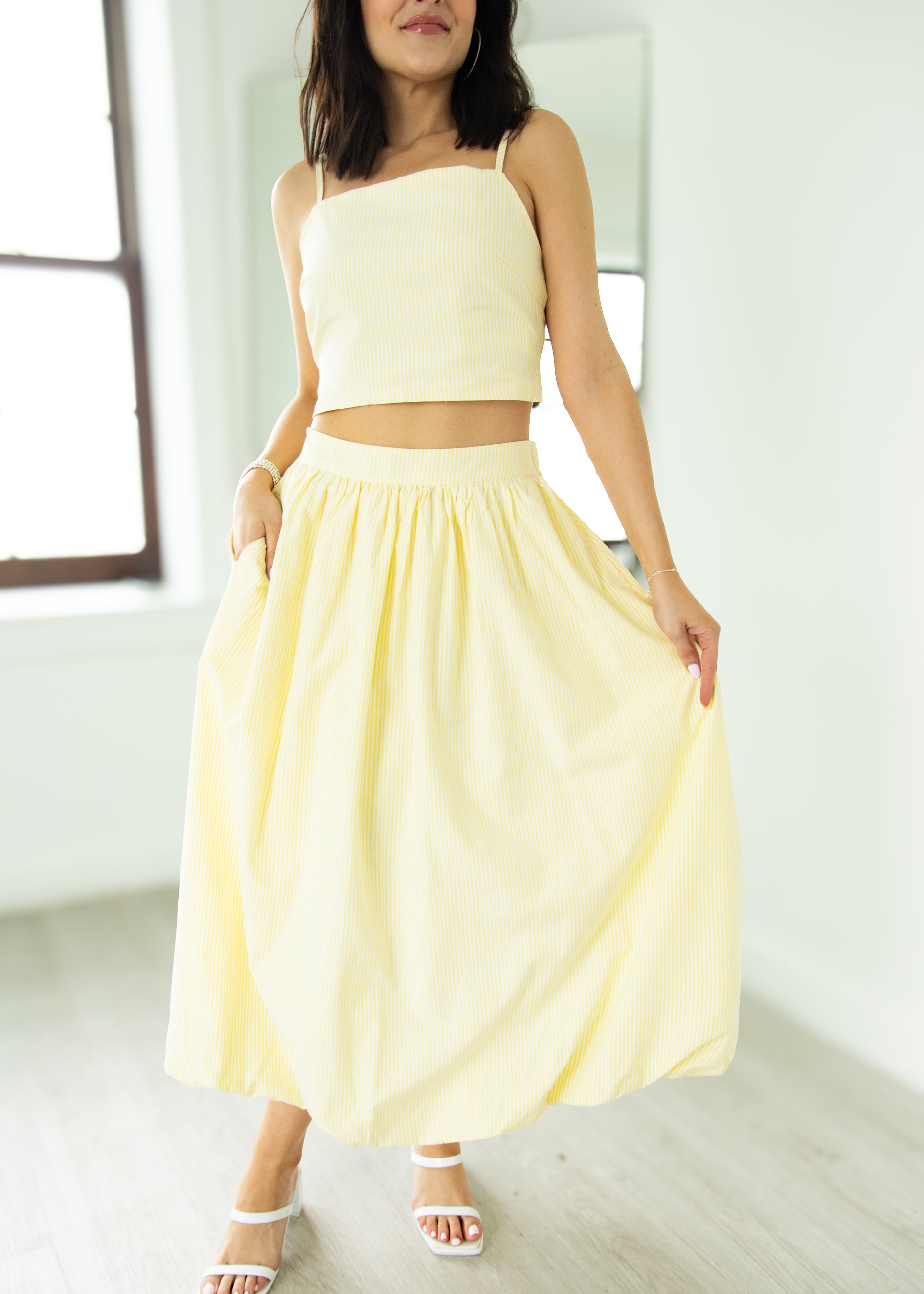 Woman wearing a light yellow two-piece outfit in a minimal indoor setting