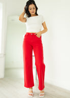 Woman wearing a white top and red pants against a plain background