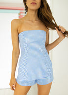 Woman wearing a blue checkered strapless romper against a white background