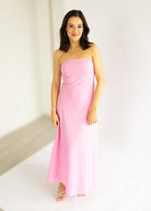Woman wearing a pink strapless dress against a white background
