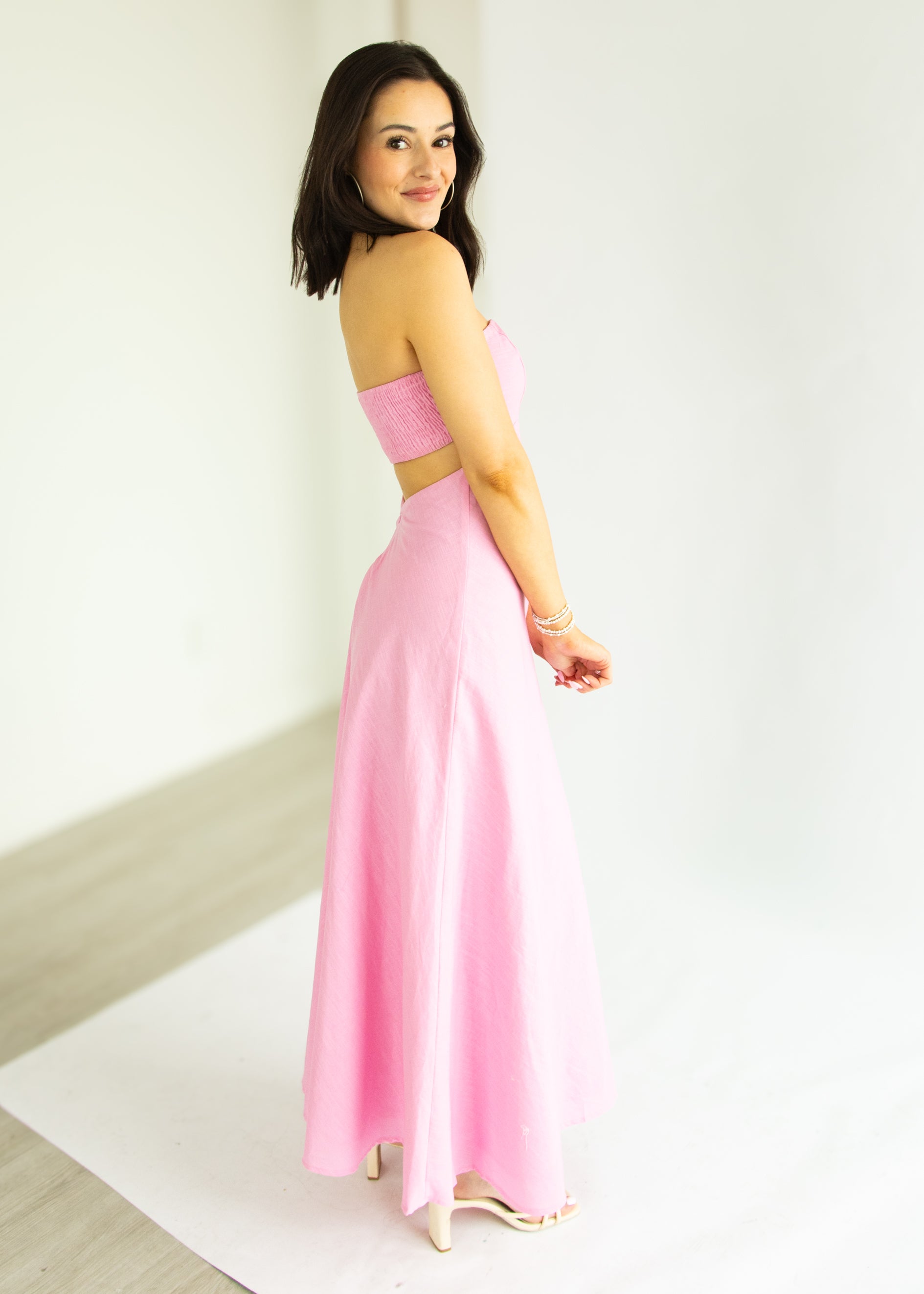 Woman wearing a pink strapless dress against a white background