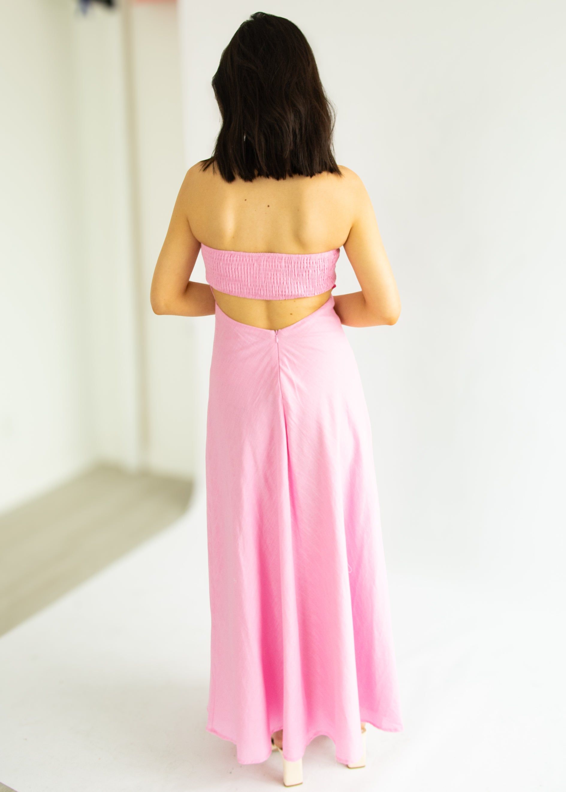 Woman wearing a pink dress with a white background