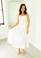 Woman wearing a white strapless dress in a bright room