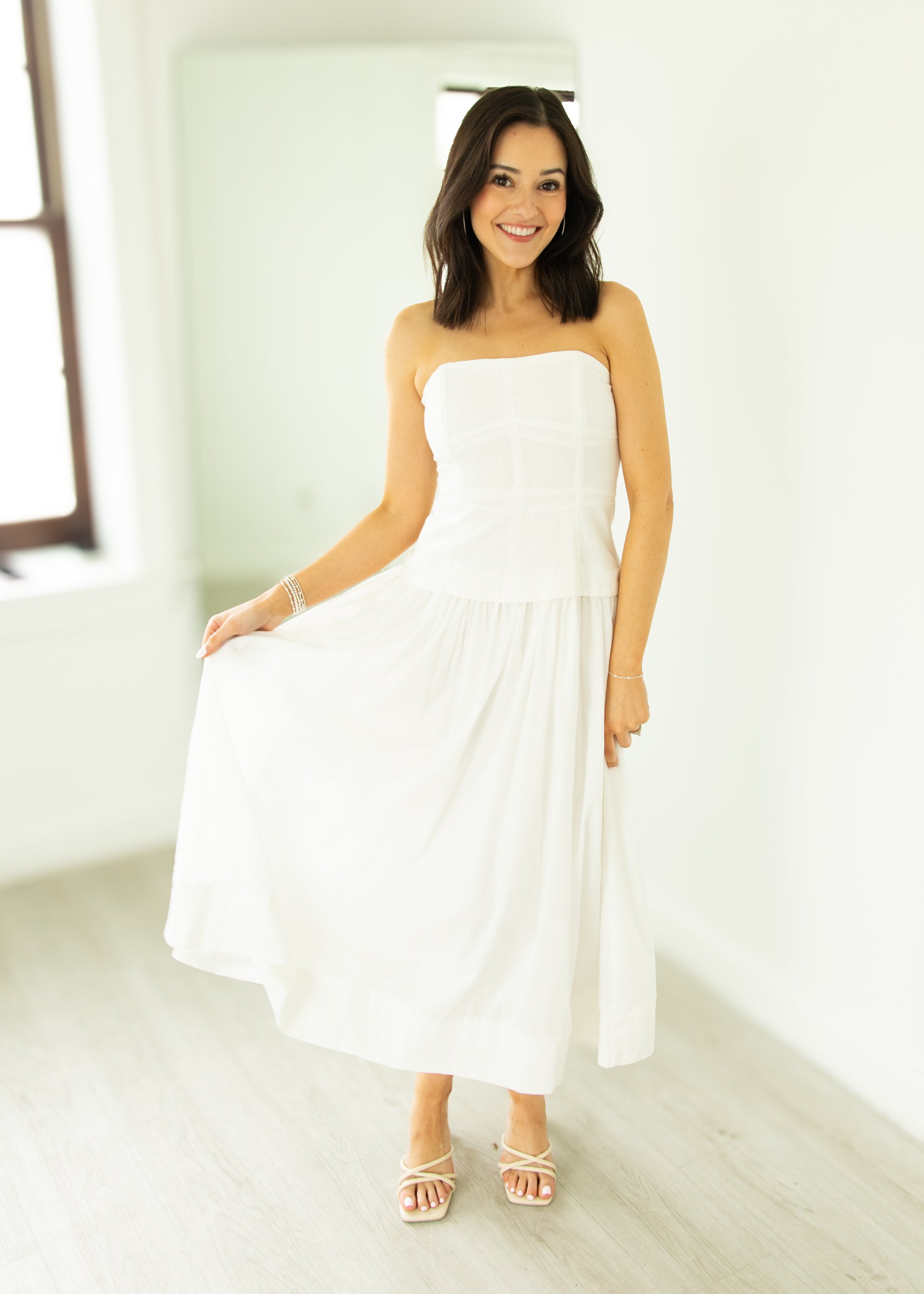 Woman wearing a white strapless dress in a bright room