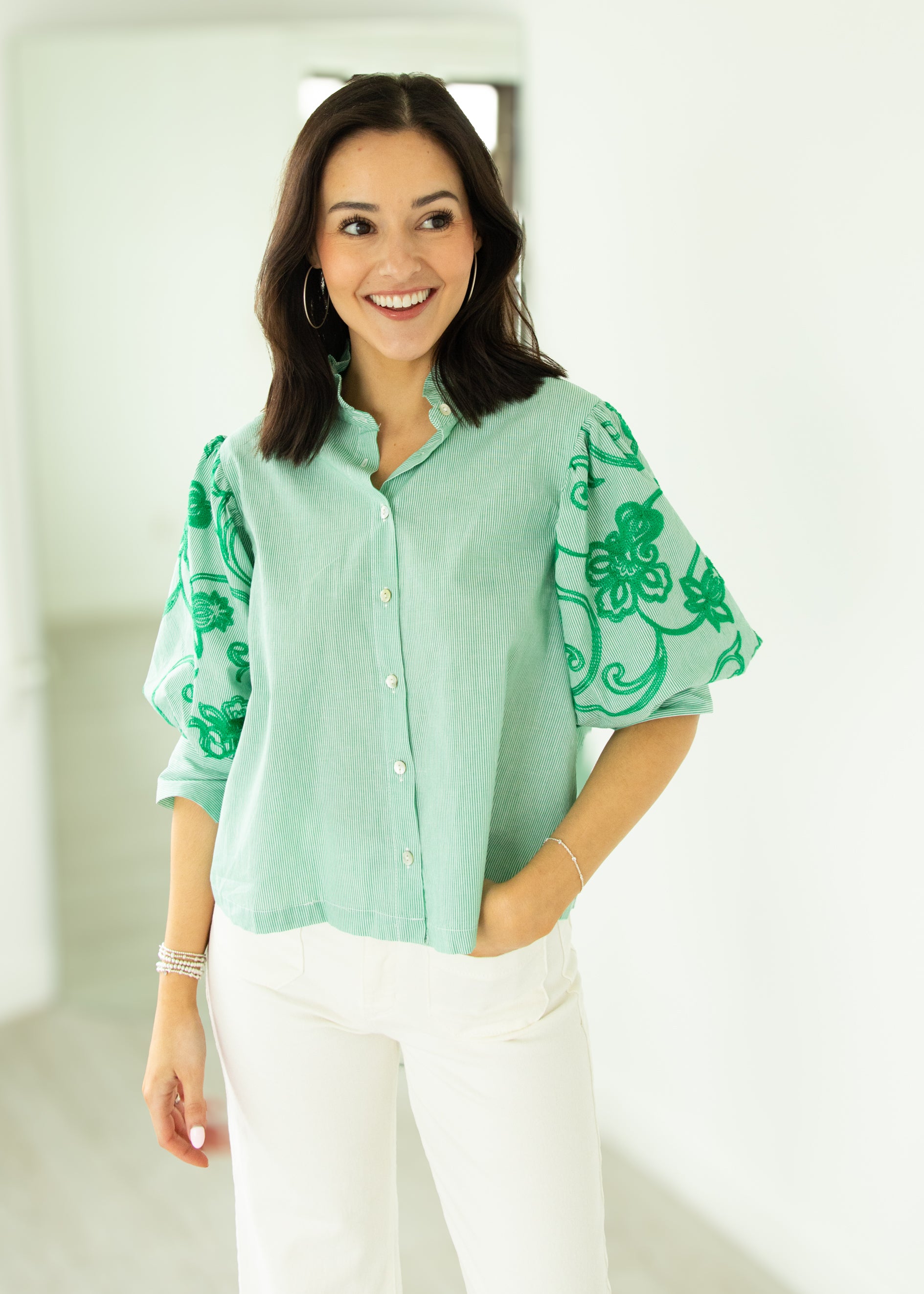 Woman wearing a light green blouse with floral patterns on a white background