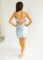 Woman wearing a light blue dress with a backless design on a white background