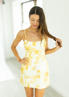 Woman wearing a yellow floral dress against a white background