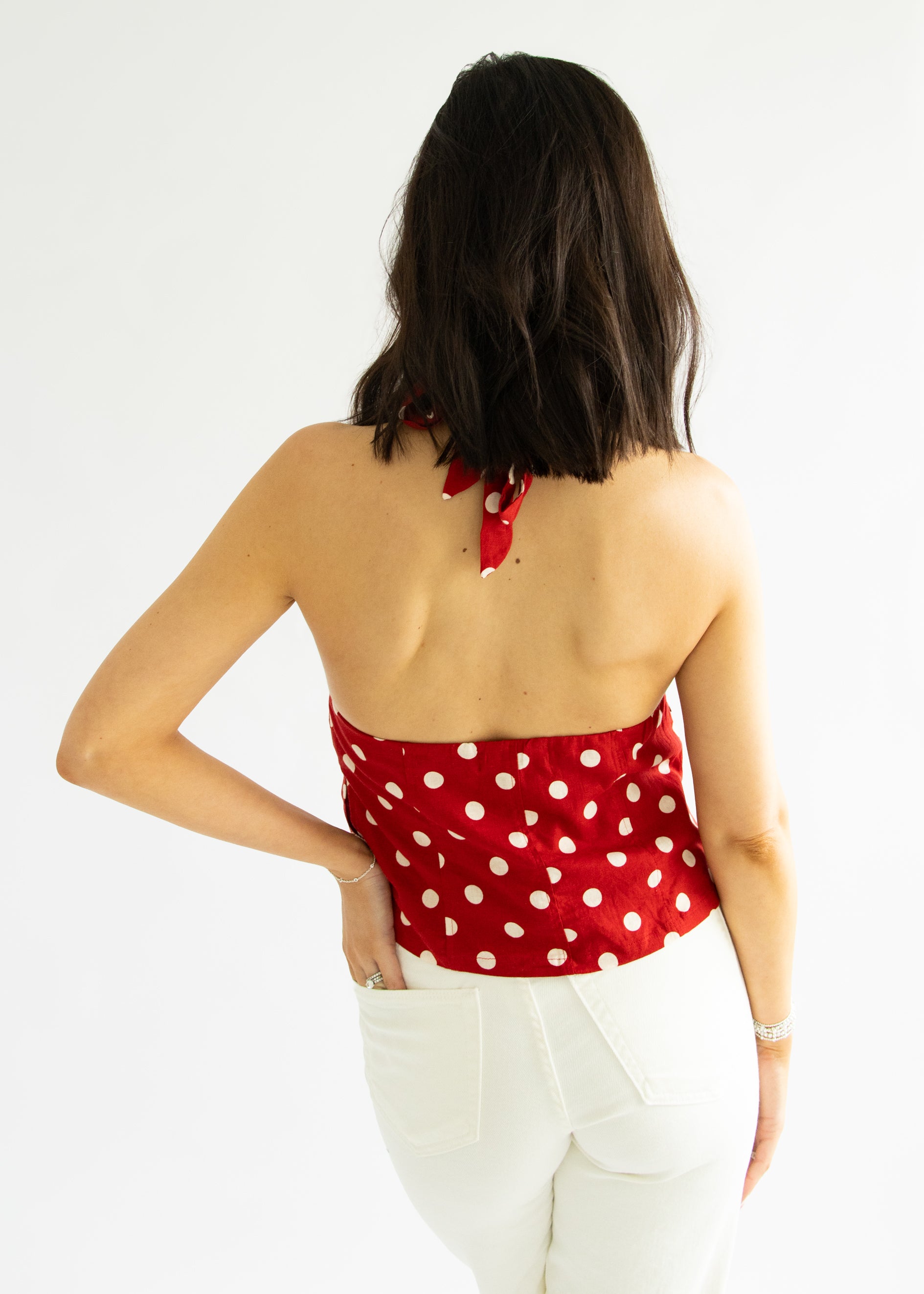 Woman wearing a red polka dot top with a white background