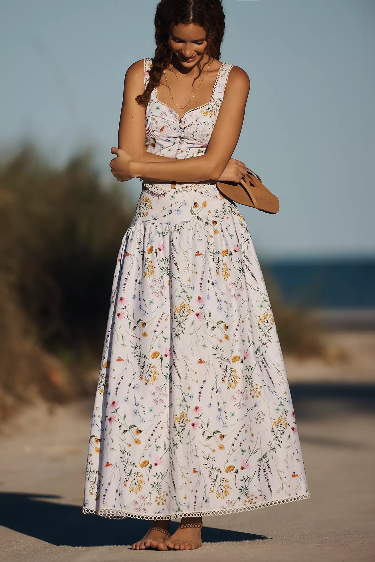 Woman in a floral dress standing on a beach with a blurred background