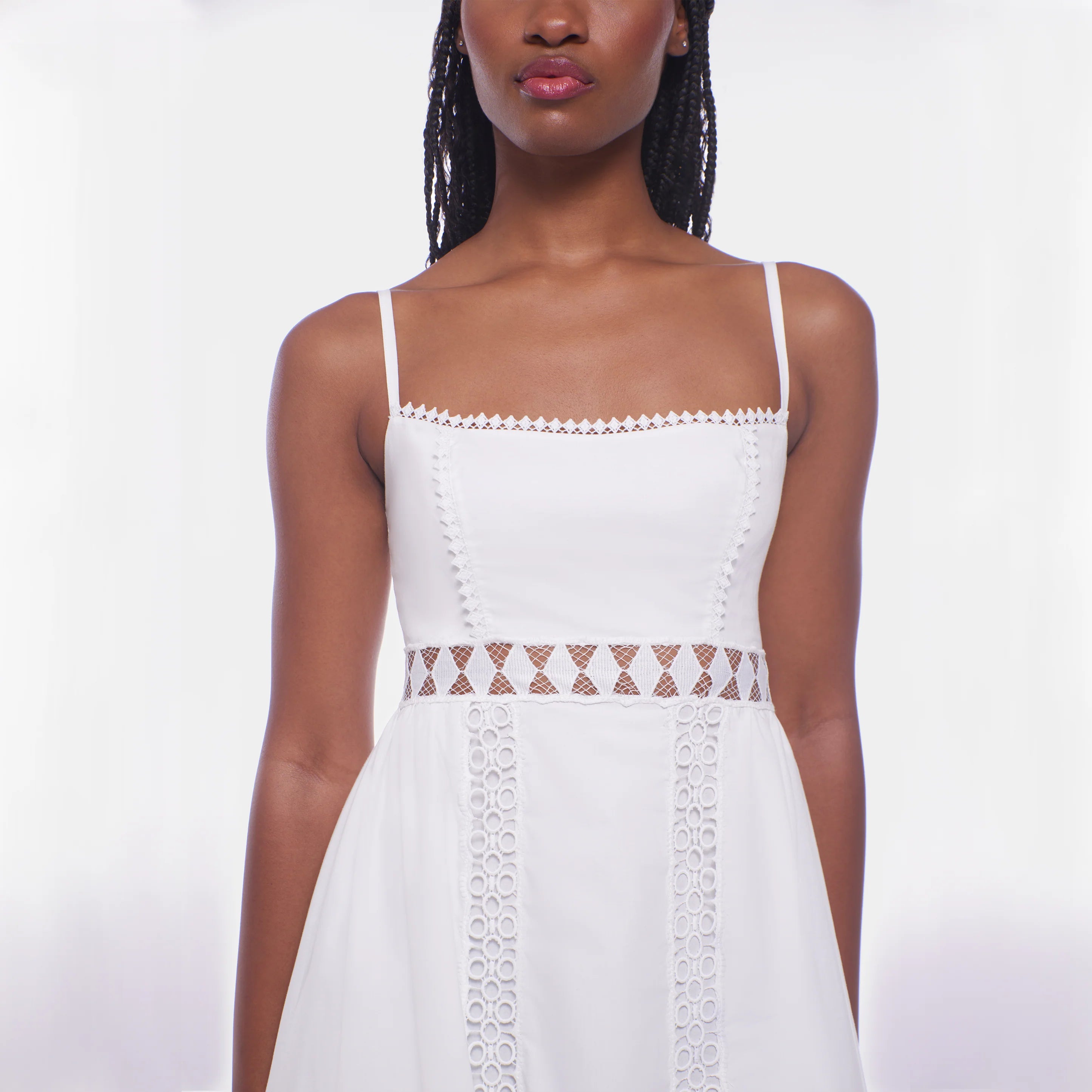 White dress with lace details worn by a model on a white background