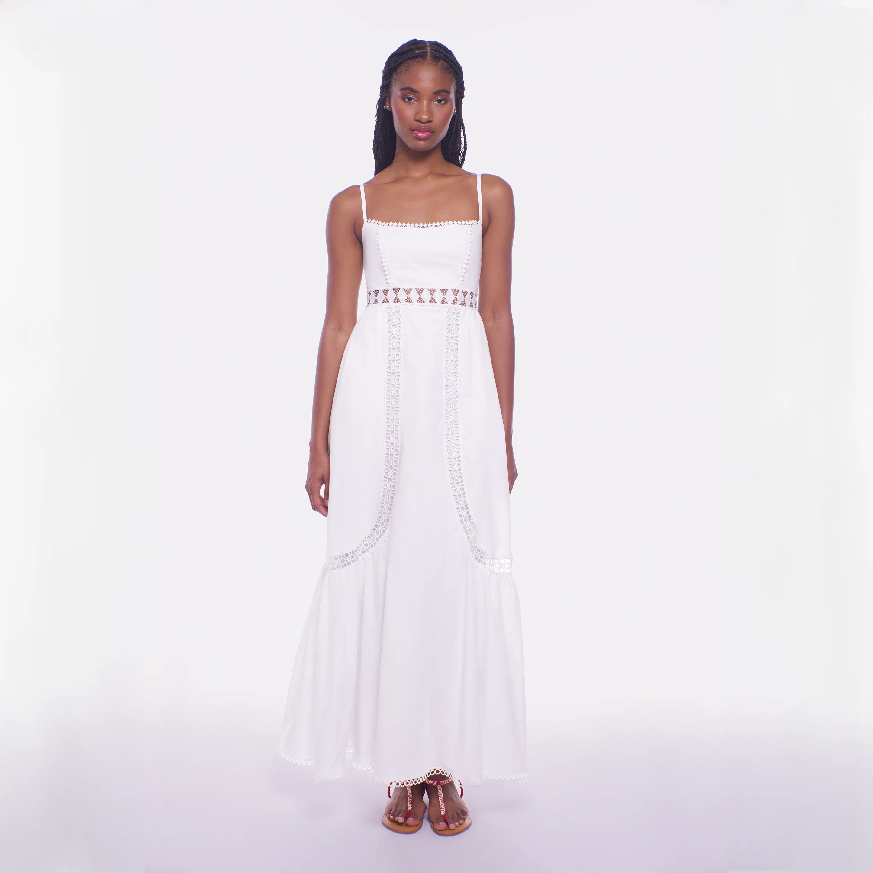 Woman wearing a white dress with decorative elements on a plain background