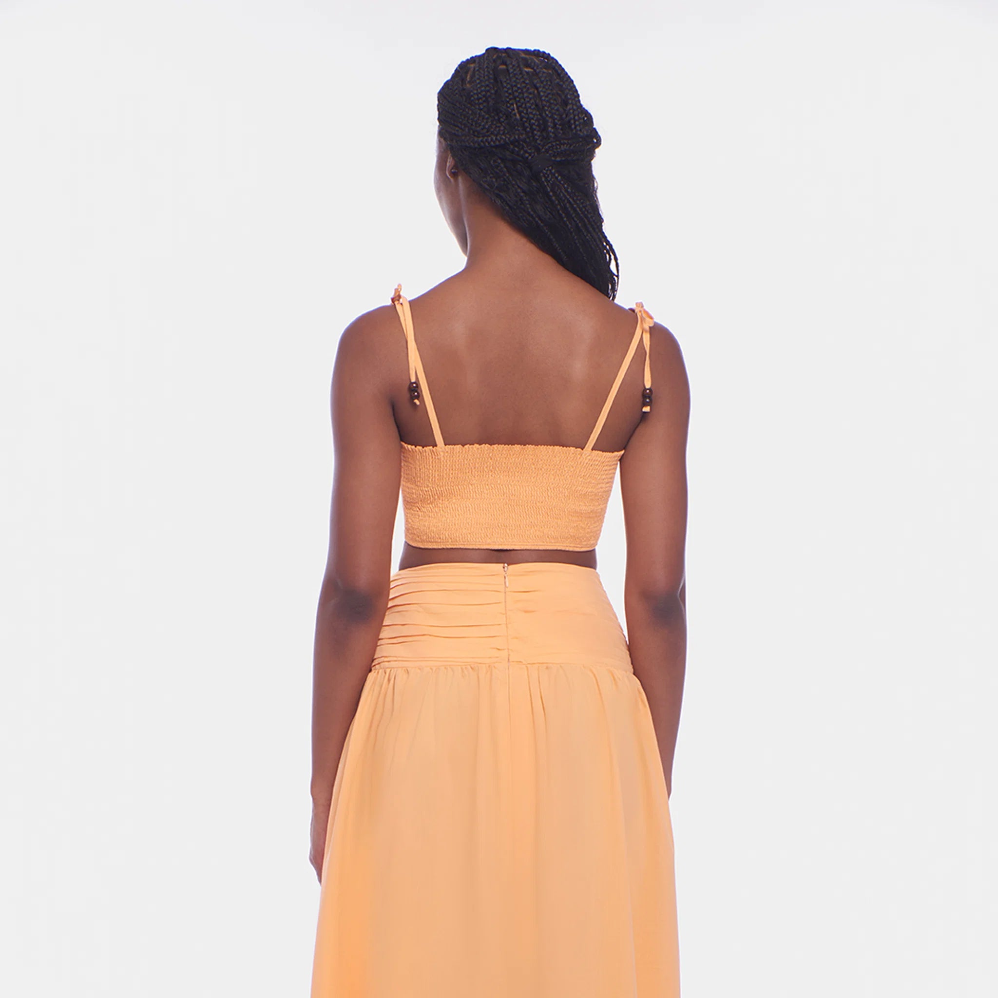Woman wearing a mustard yellow two-piece outfit on a white background