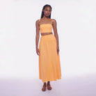 Woman wearing a yellow two-piece outfit on a white background