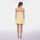 Woman wearing a yellow dress with floral straps on a white background