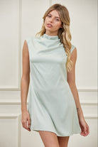 Woman wearing a light blue dress against a white wall