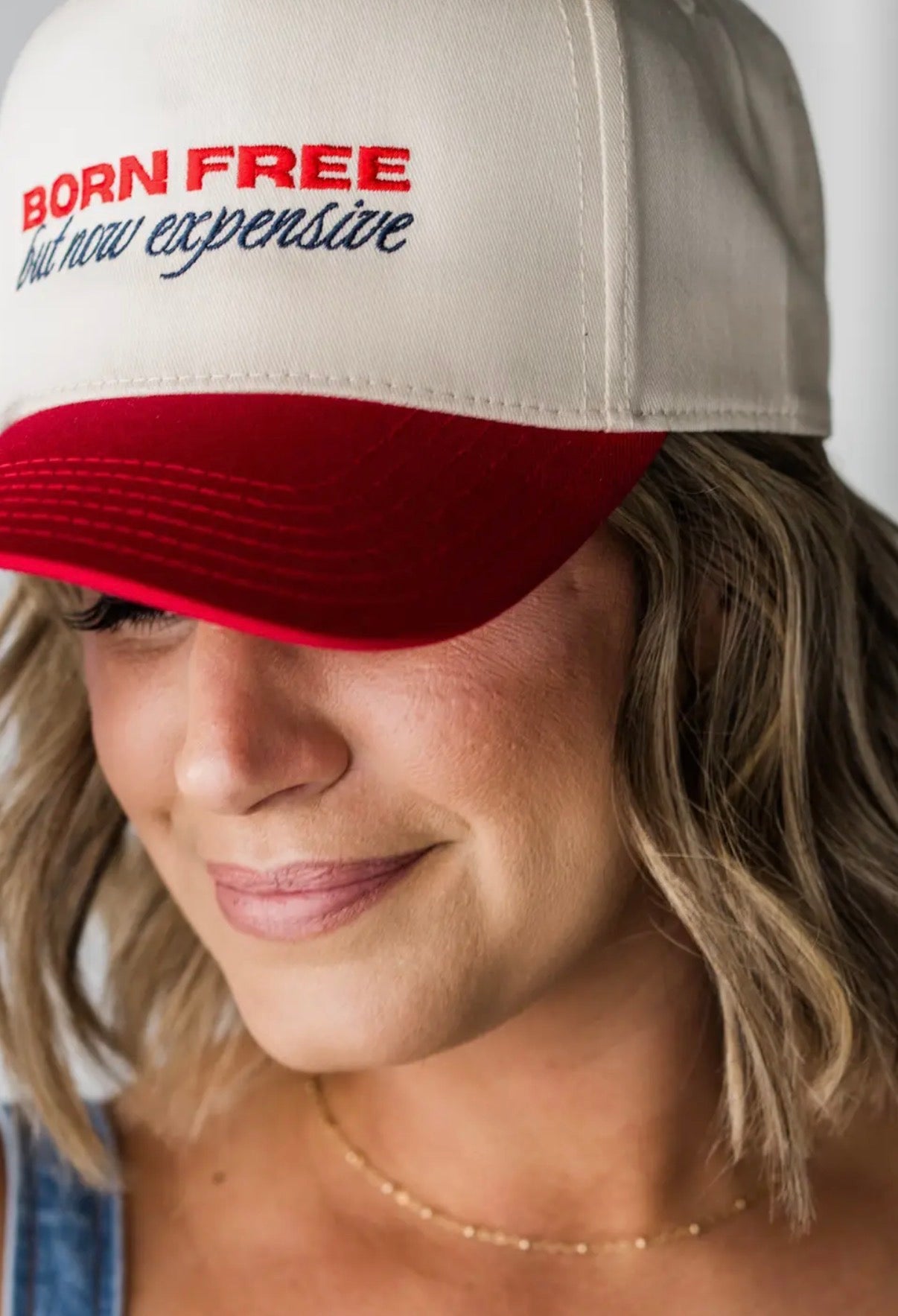 Person wearing a cap with 'Born Free but now expensive' text
