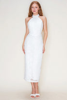 Woman wearing a white halter neck dress against a plain background