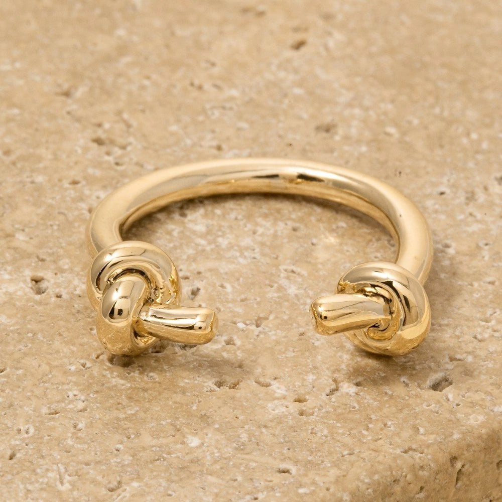 Gold knot ring on a beige stone surface