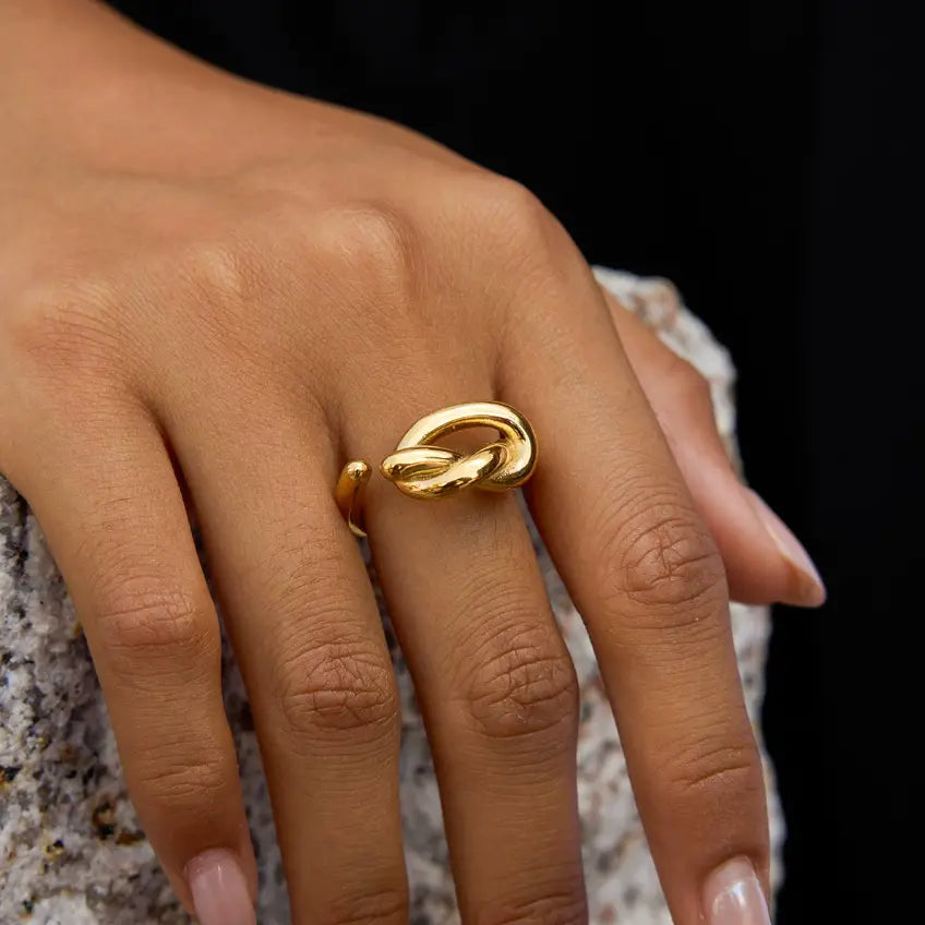 Gold ring on a person's finger against a dark background