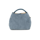 A dusty blue suede handbag with a top handle, photographed against a solid white background.
