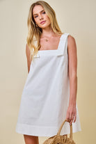 Woman wearing a white dress against a beige background