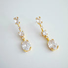 Gold earrings with clear gemstones on a light gray background