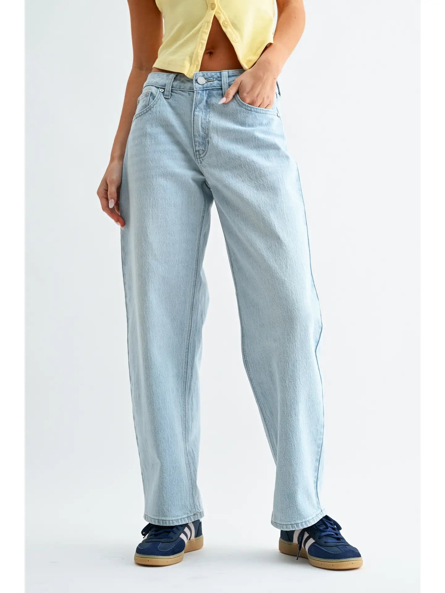 Person wearing light blue jeans and a yellow top on a white background