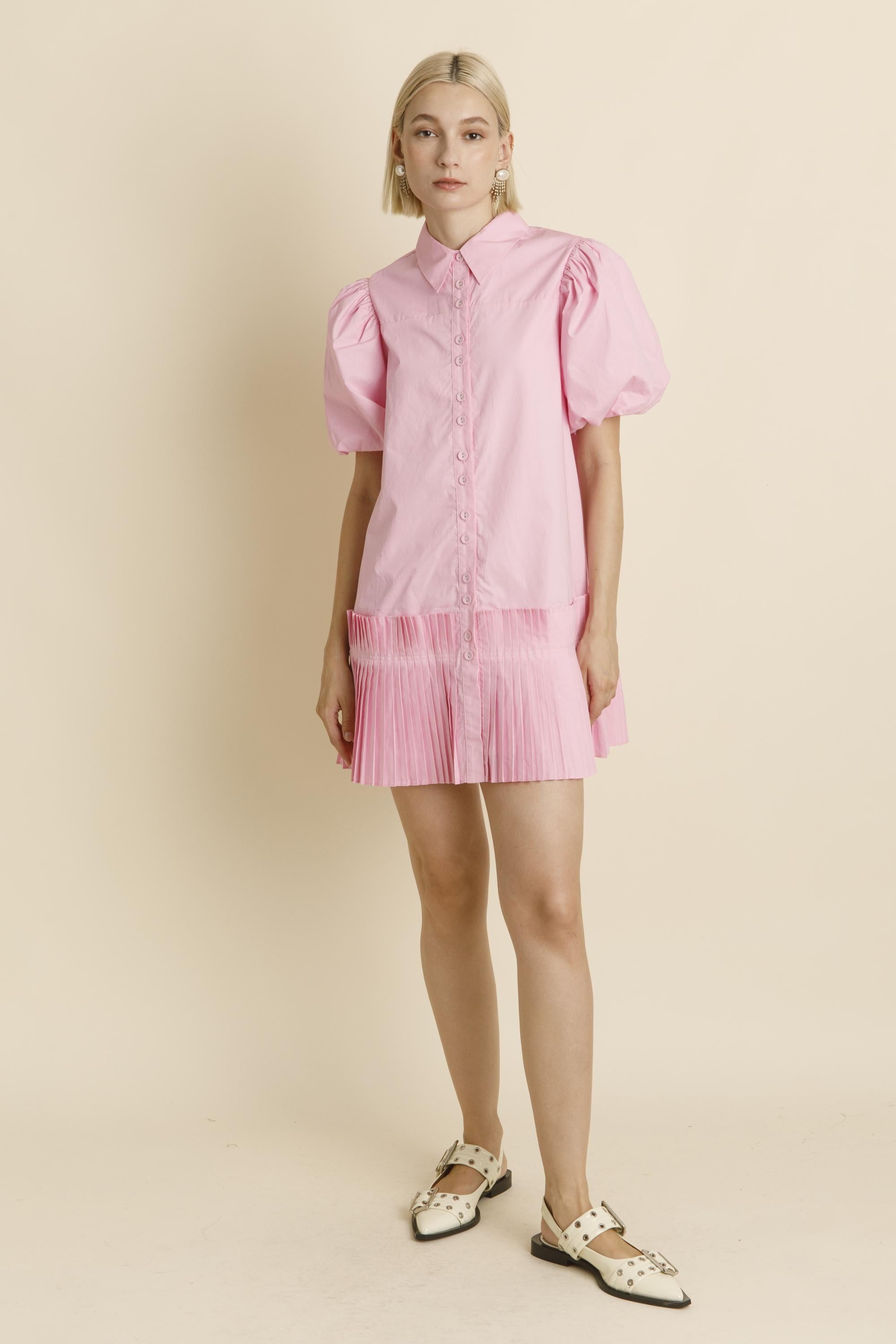 Woman wearing a pink dress with puffed sleeves on a beige background
