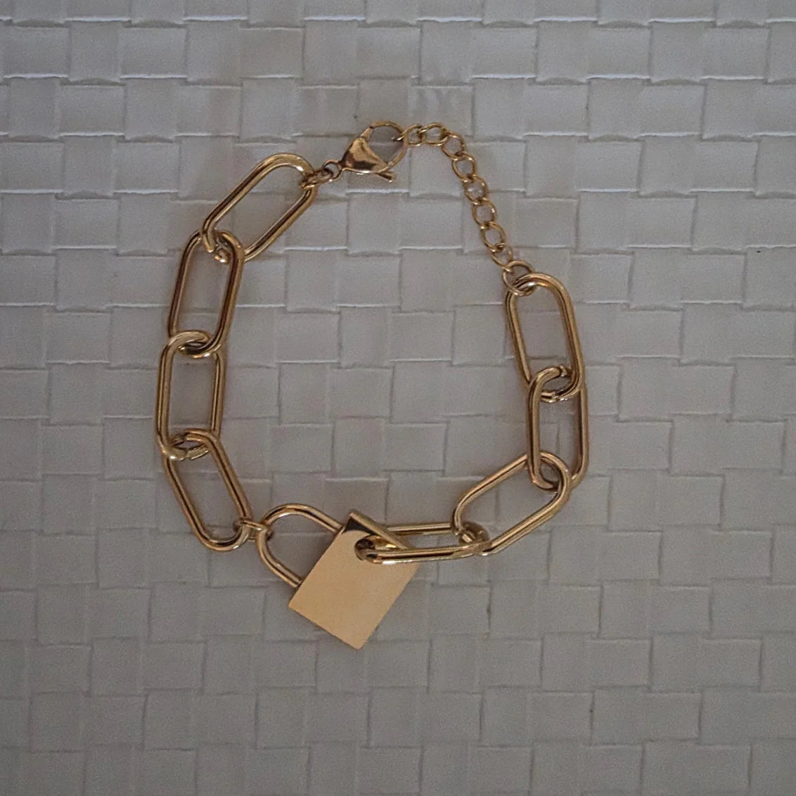 Gold chain bracelet with a tag on a textured gray background