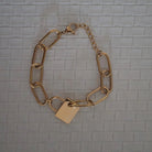 Gold chain bracelet with a tag on a textured gray background