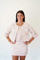 Woman wearing a striped dress with a matching jacket on a white background