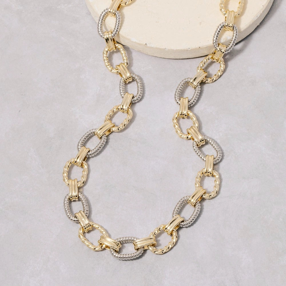 Gold and silver chain necklace on a light gray background