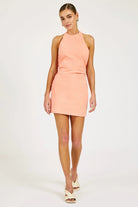 Woman wearing a peach halter dress on a white background