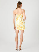 Woman wearing a yellow floral dress on a white background