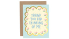 Greeting card with 'Thank you for thinking of me' text on a light blue background with floral design, next to a brown envelope.