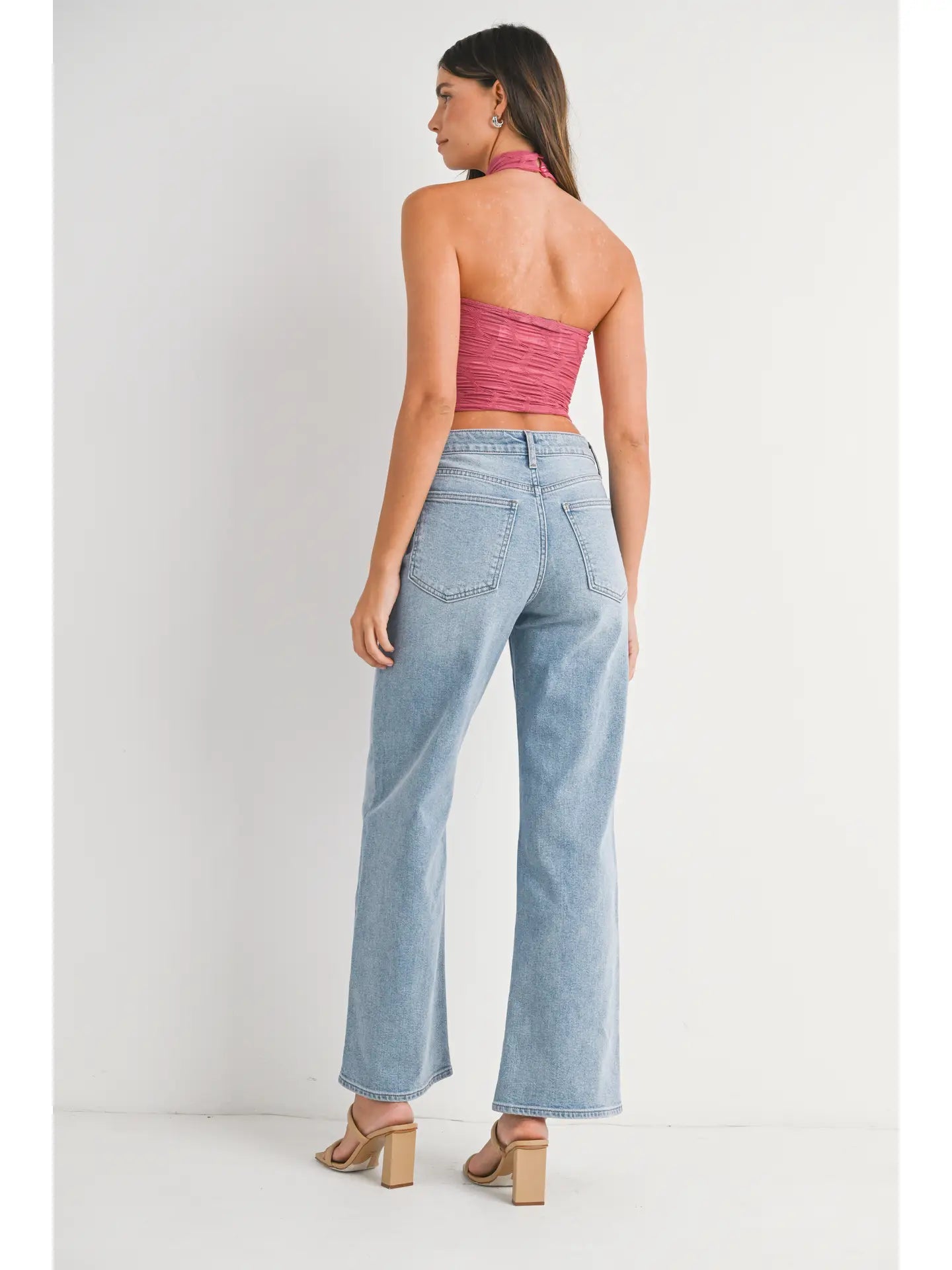 Woman wearing a pink strapless top and light blue jeans on a white background