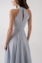 Woman wearing a light blue halter neck dress against a white background