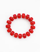 A beaded stretch bracelet made of glossy, rounded red beads separated by small gold spacer beads, shown on a plain white background.