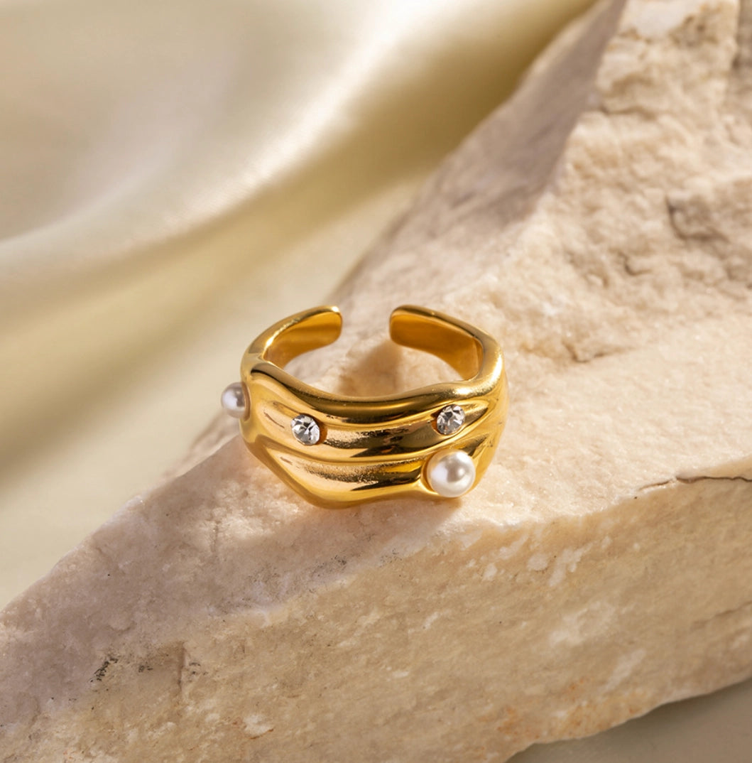 Gold ring with pearls and small stones on a stone surface