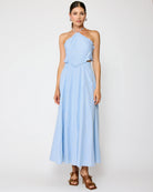 Woman wearing a light blue halter neck dress on a white background