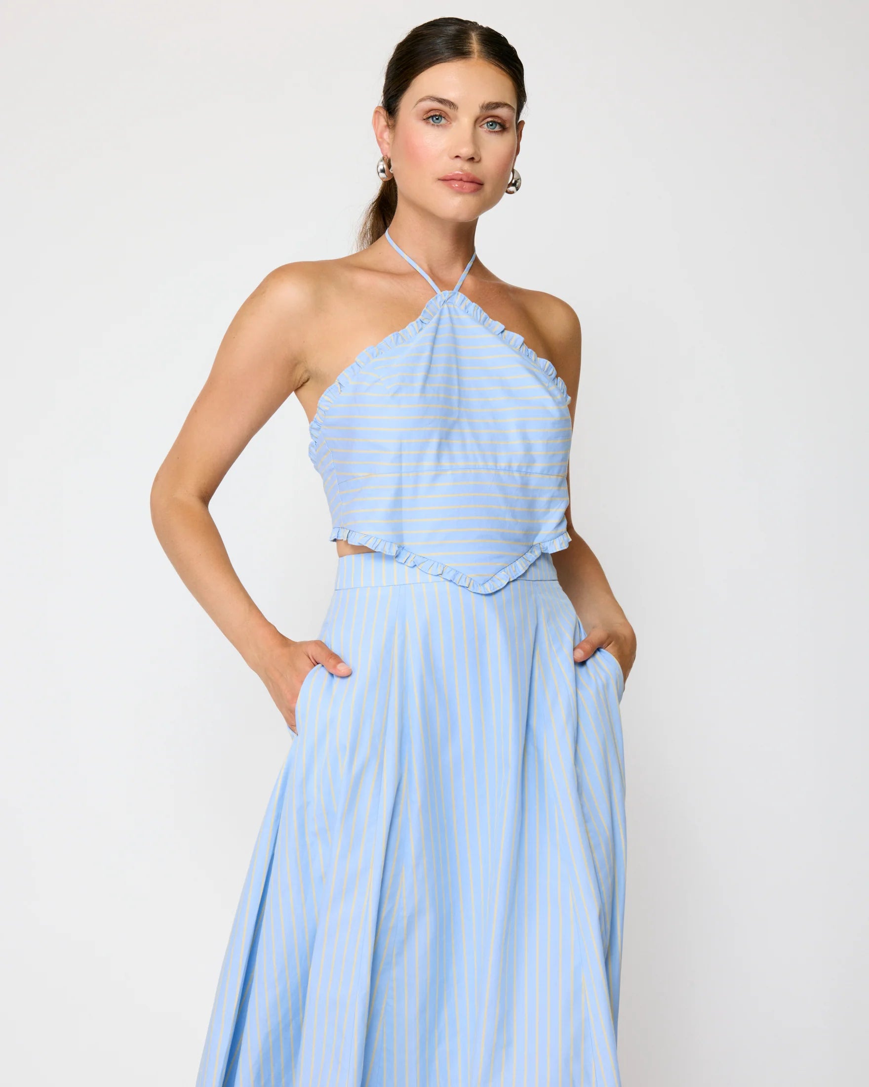 Woman wearing a light blue halter neck dress against a plain background