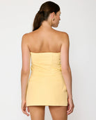 Woman wearing a light yellow skirt standing in a room with a white door.