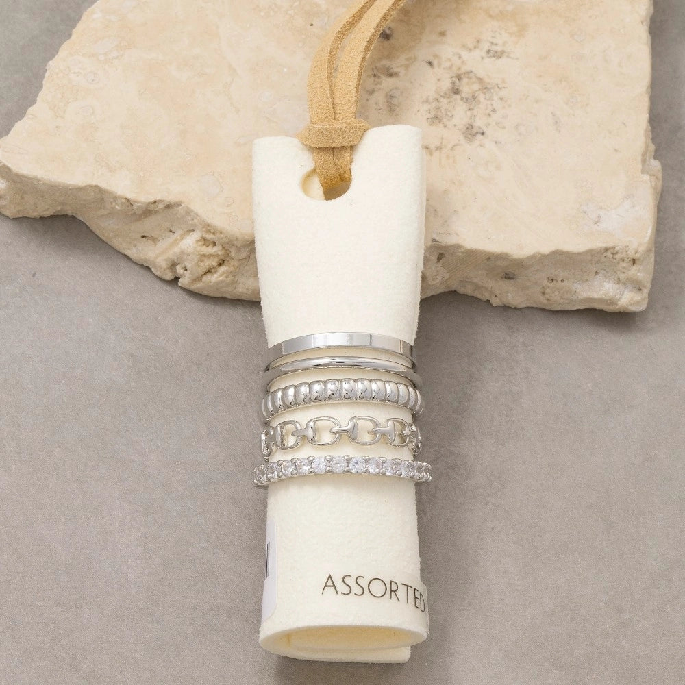 Assorted silver rings in a cylindrical holder on a stone surface