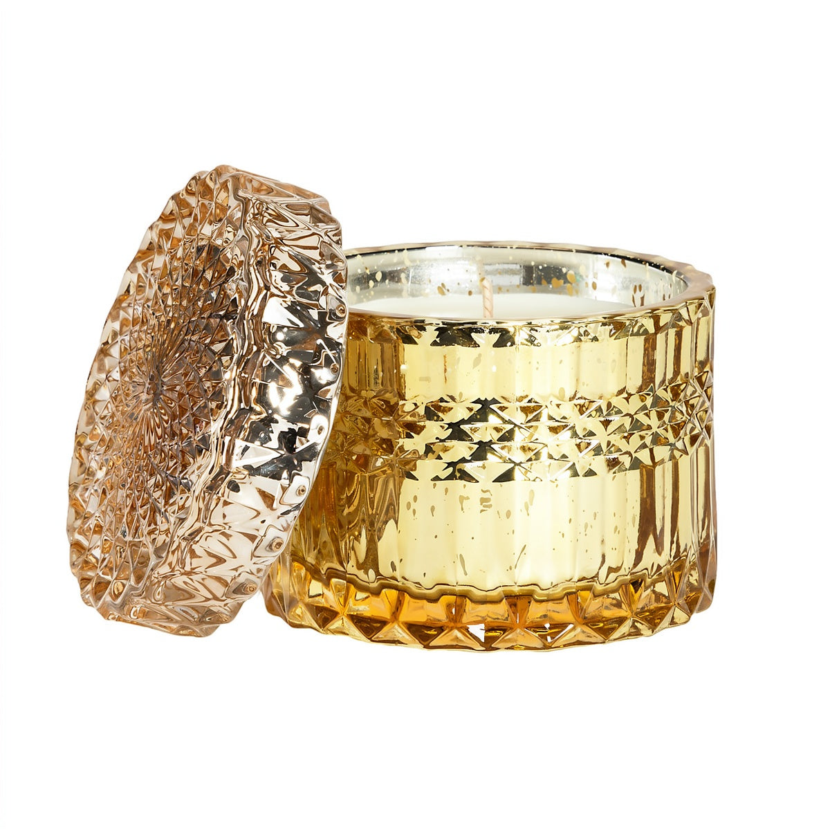 A gold-toned textured glass candle jar with its matching faceted lid leaning against it, shown on a plain white background.