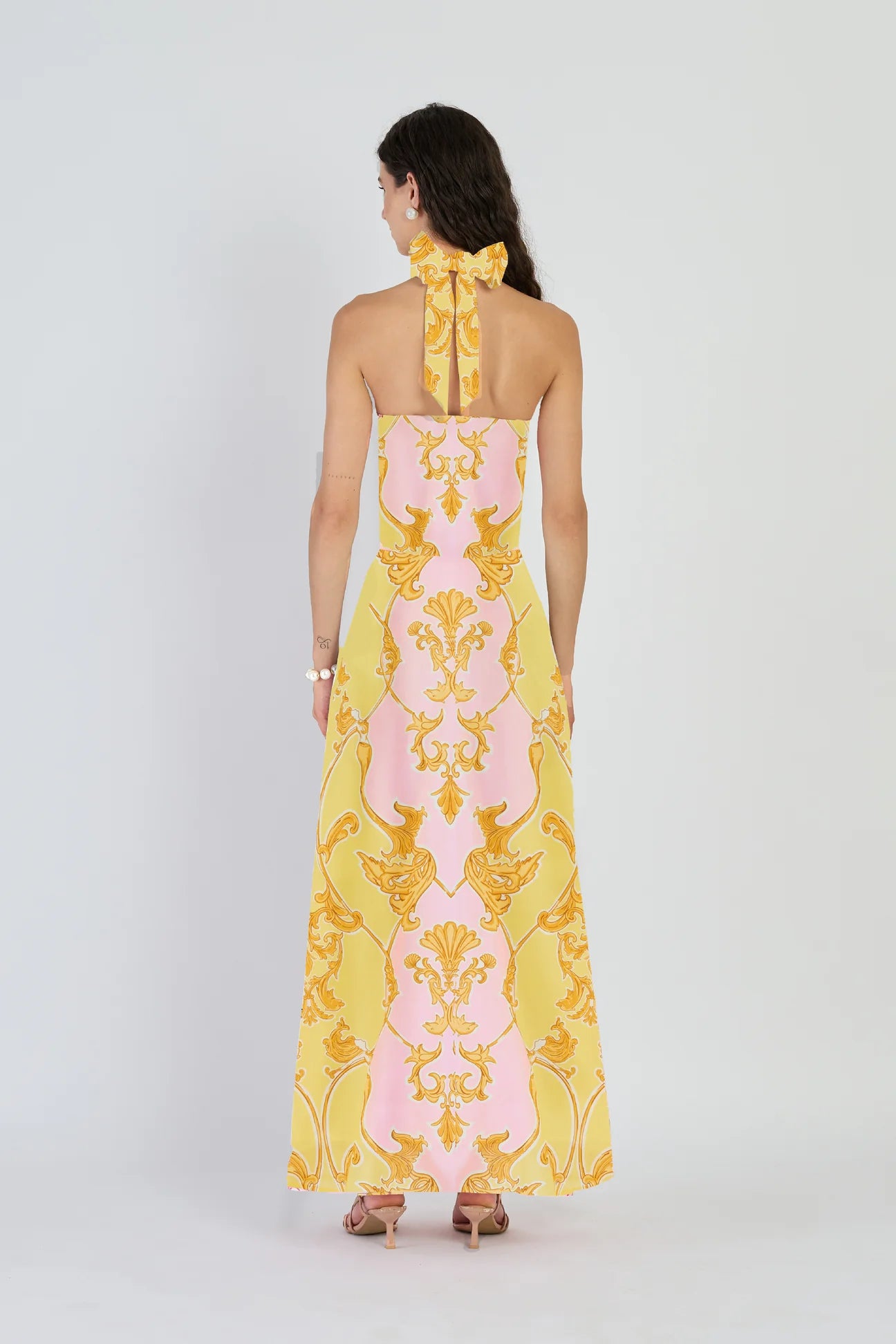 Woman wearing a yellow and pink patterned dress on a white background